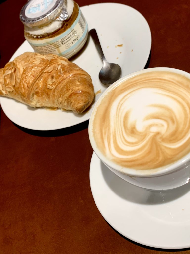 Breakfast croissant and cappuccino with yogurt at Illy at the Genoa train station, Italy